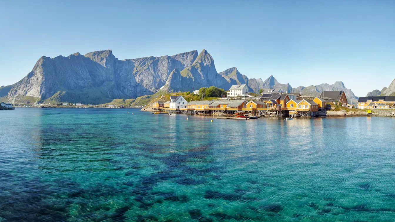 Gula hus på brygga i Lofoten med hav och fjäll runt omkring.