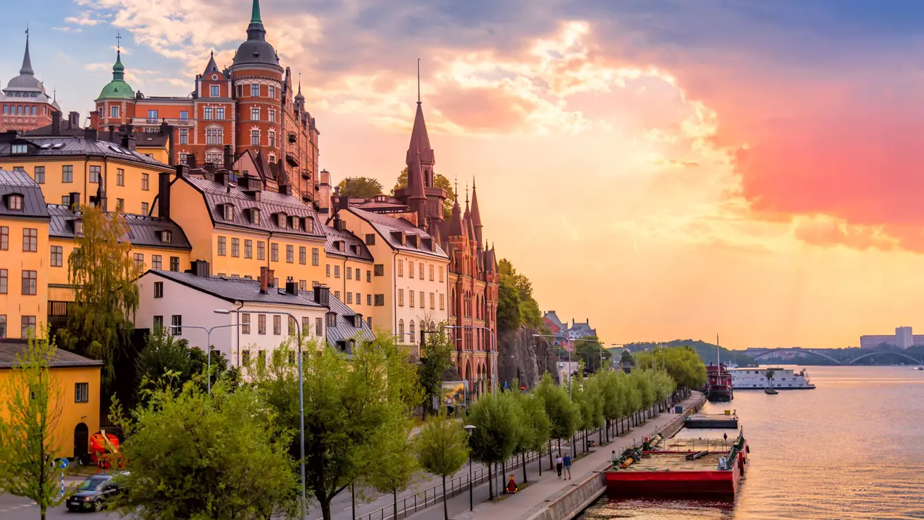 Södermalms gamla malmgårdar till vänster, promenadväg och båthamn till höger. Solnedgång.