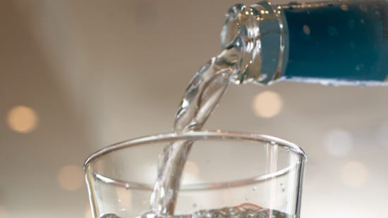 Wasser, das aus der Flasche in ein Glas gegossen wird.