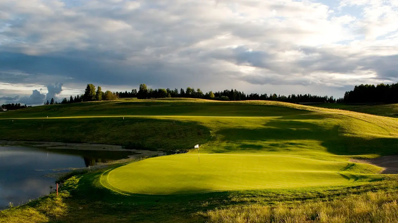 Golf course with a pond and green grass.